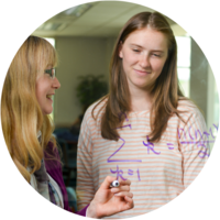 A female student and professor solve math equation on a whiteboard.